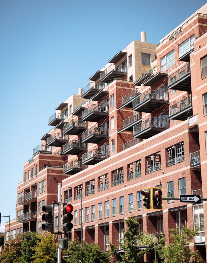 about-06 Contemporary brick apartment building with balconies in cityscape.
